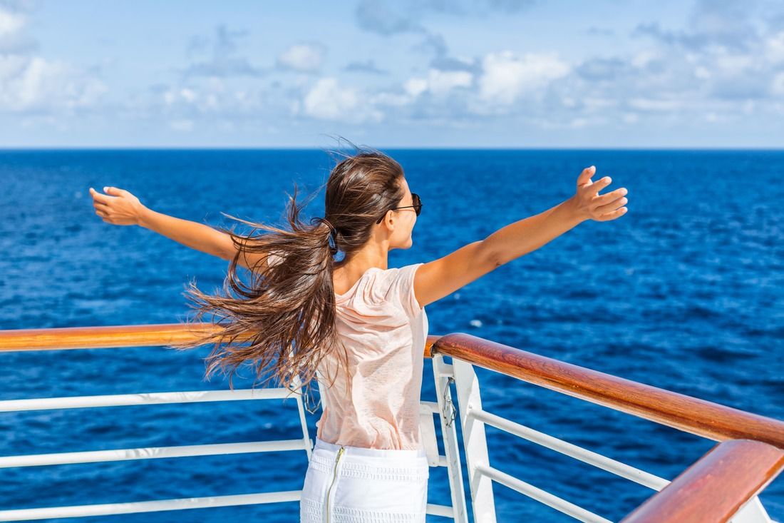 Caucasian woman spreading arms out off cruise ship rail